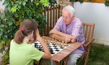 Une personne âgée et une petite fille jouent aux échecs
