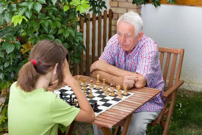 Une personne âgée et une petite fille jouent aux échecs